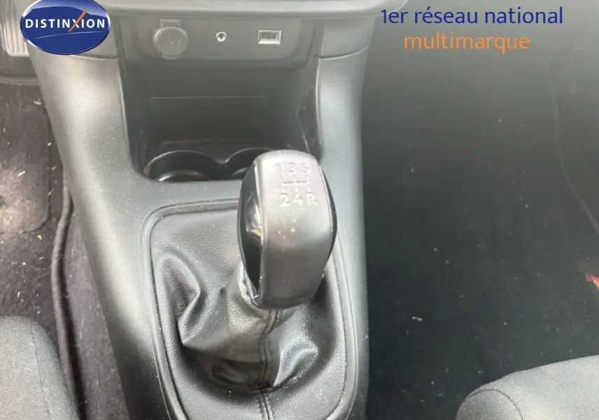 Le levier de vitesses manuel noir de la Citroën C3 blanche, vu en gros plan depuis l'intérieur avant.