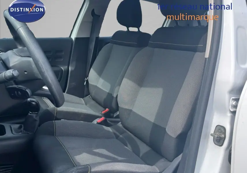 Vue intérieure côté conducteur d'une Citroën C3 blanche 2018, sièges tissu gris avec surpiqûres contrastantes.