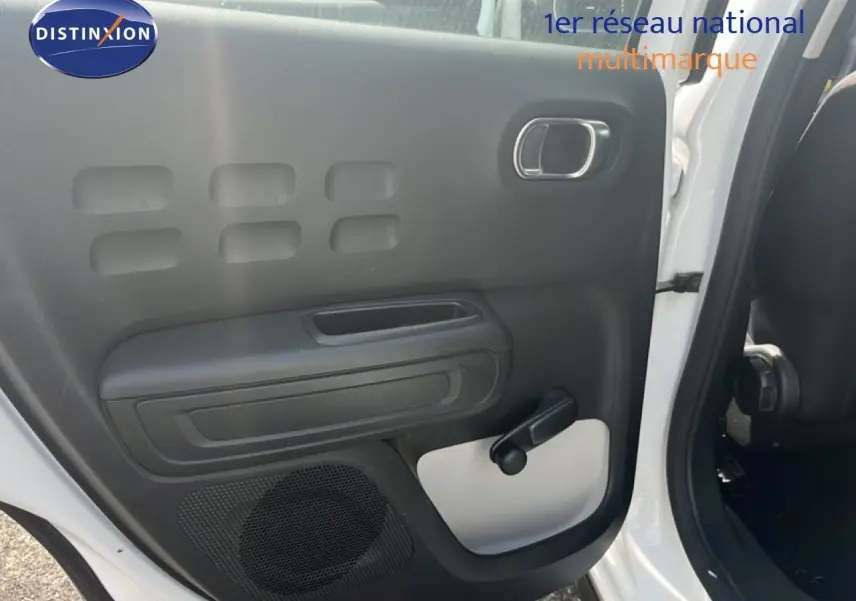 Vue intérieure de la porte arrière gauche d'une Citroën C3 blanche 2018 avec poignée de vitre manuelle et haut-parleur intégré.