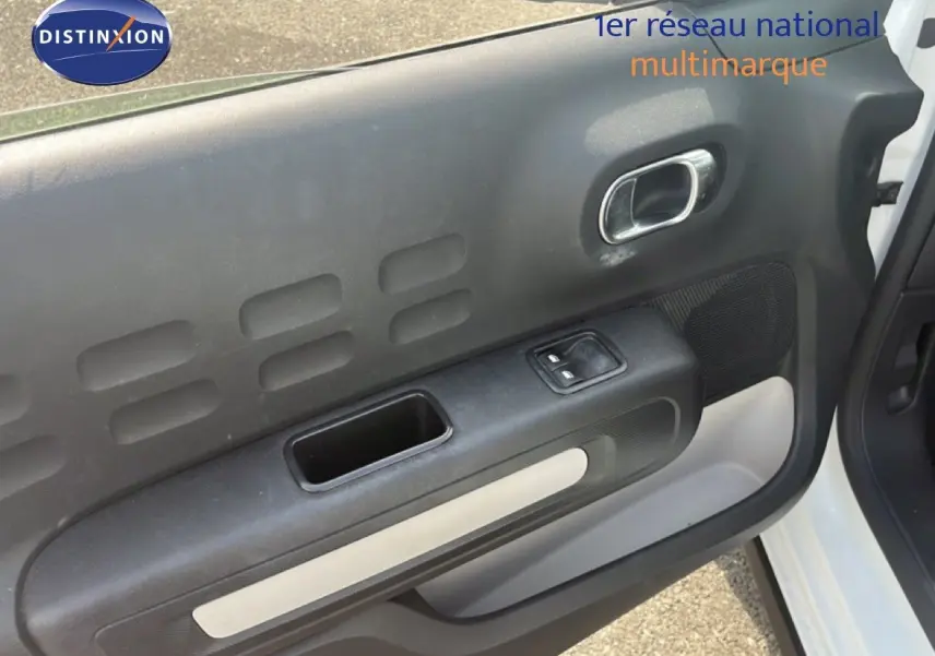 Vue rapprochée de la porte avant gauche blanche d'une Citroën C3 2018, mettant en valeur la poignée et les commandes électriques.