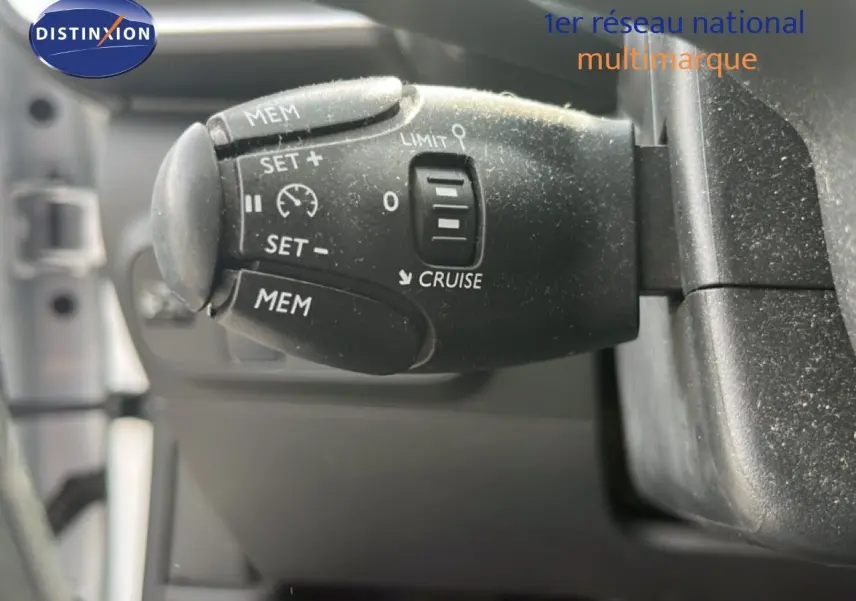Gros plan sur la commande de régulateur de vitesse noire dans l'habitacle d'une Citroën C3 blanche de 2018.