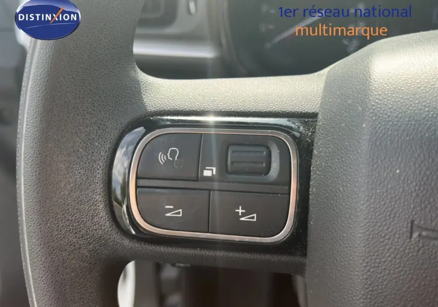 Gros plan sur les commandes de volume et téléphone au volant d'une Citroën C3 blanche, version 2018.