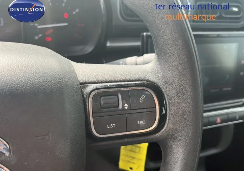 Gros plan sur les commandes au volant d'une Citroën C3 2018 essence, mettant en valeur les boutons de gestion audio et téléphone.