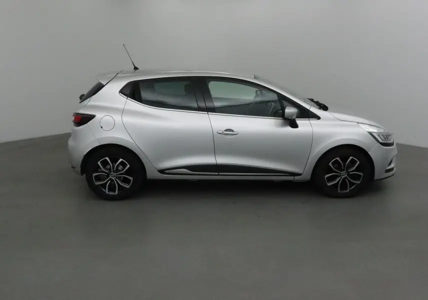 Profil droit d'une Renault Clio IV gris clair métal de 2018 avec jantes biton et lignes fluides modernes.
