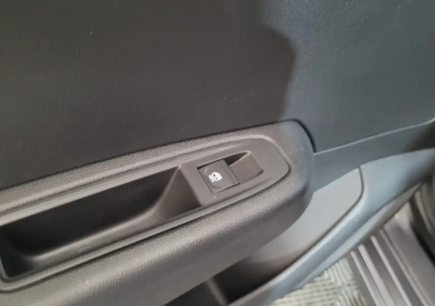 Bouton de commande de la vitre électrique sur la portière intérieure côté conducteur d'une Renault Clio gris foncé.