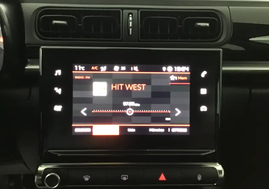 Vue rapprochée de l’écran tactile central du tableau de bord de la Citroën C3 2022, affichant la radio FM sur Hit West.