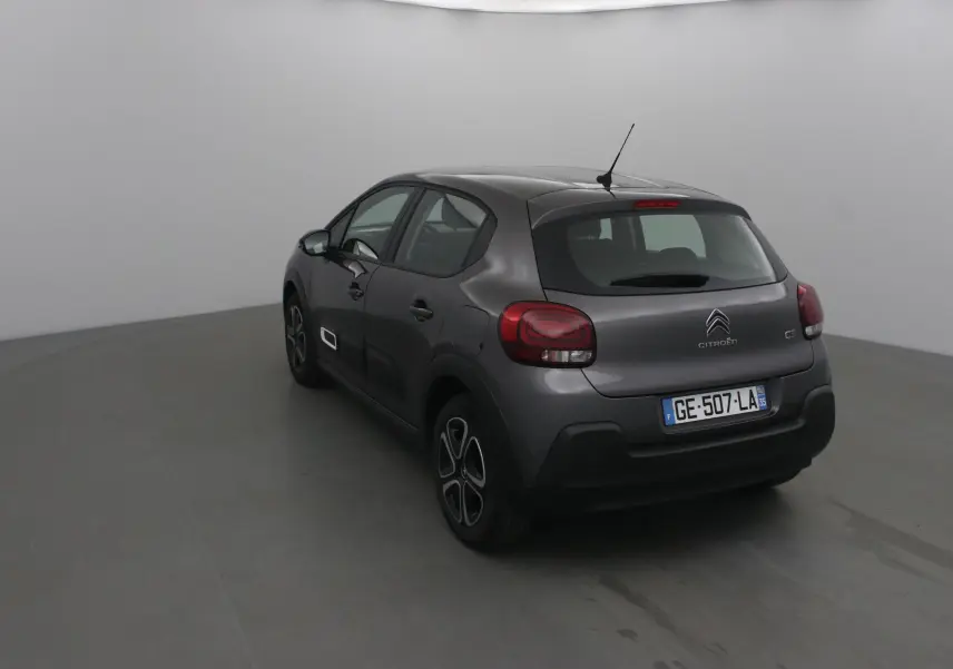 Vue 3/4 arrière gauche d'une Citroën C3 gris platinium 2022 avec feux arrière arrondis et jantes stylisées.