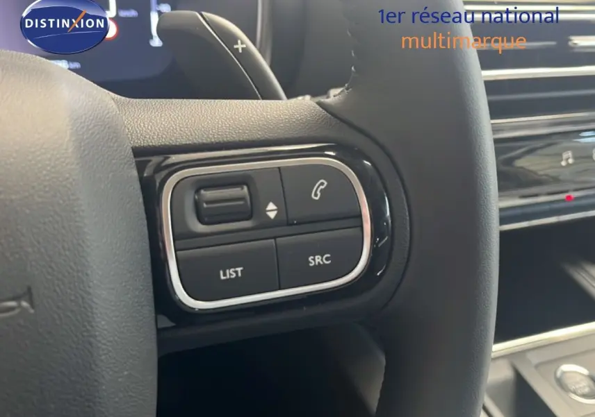 Gros plan sur les commandes au volant noir du Citroën C5 Aircross 1.2 Hybride 2025, intérieur noir métal.