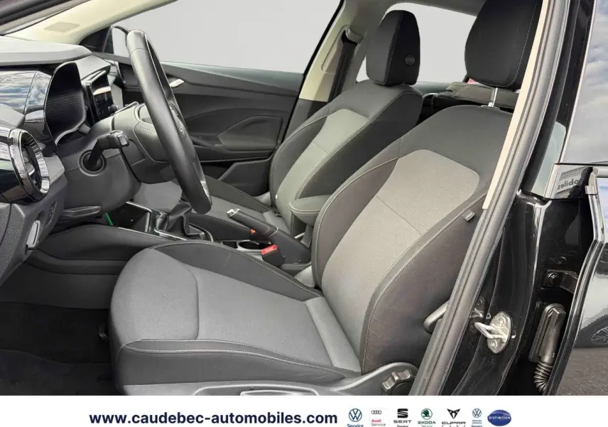 Vue intérieure côté conducteur de la Skoda Fabia noire 2025, montrant sièges tissu gris et volant cuir multifonctions.