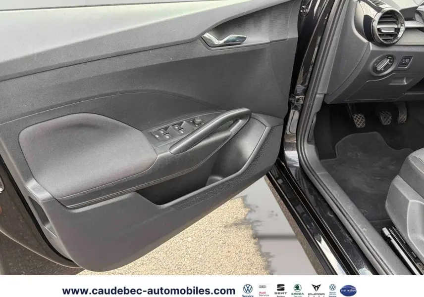Vue intérieure côté conducteur de la porte noire ouverte d’une Skoda Fabia 2025 avec commandes de vitres et rétroviseurs.