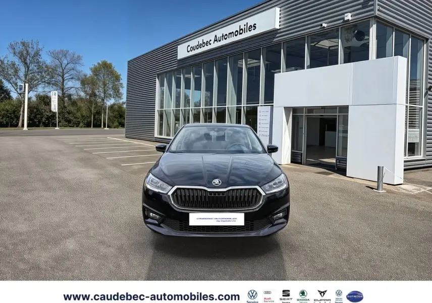 Vue frontale d'une Skoda Fabia noire 2025 stationnée devant un bâtiment moderne de concession automobile.