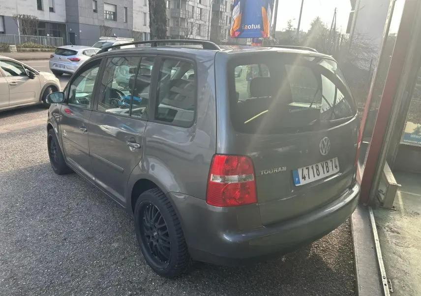 Volkswagen Touran gris 2004 vu en 3/4 arrière droit, avec jantes noires et toit ouvrant visible.