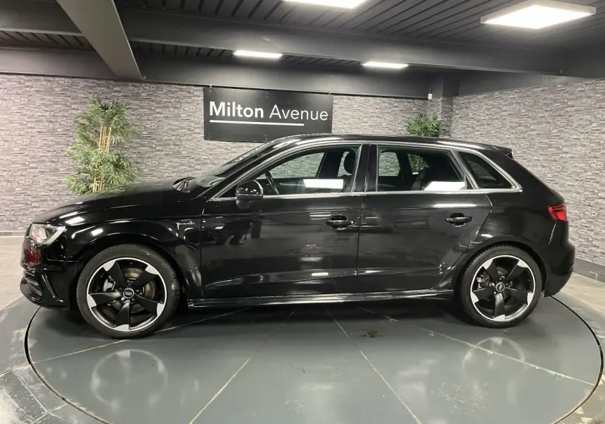 Profil côté gauche d'une Audi A3 1.4 TFSI e-tron S line noire avec jantes Audi Sport 18 pouces en intérieur showroom.