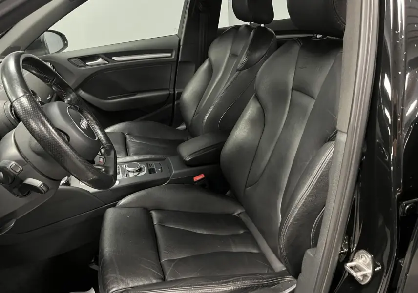 Intérieur noir de l'Audi A3 1.4 TFSI e-tron S line, vue côté conducteur avec sièges sport cuir et volant multifonction.