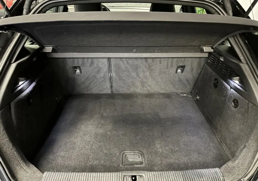 Coffre ouvert vu de face d'une Audi A3 1.4 TFSI e-tron S line noire avec intérieur de coffre en tissu gris foncé.