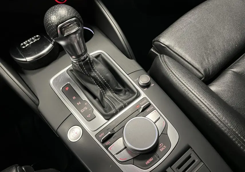 Gros plan sur la console centrale noire en cuir et aluminium de l'Audi A3 1.4 TFSI e-tron S line avec levier de vitesses automatique et commandes MMI.