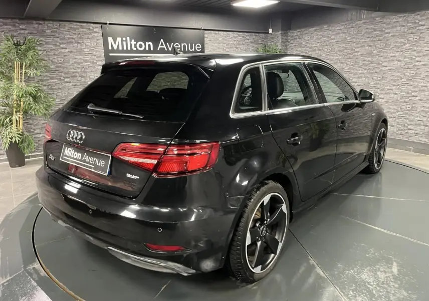 Audi A3 1.4 TFSI e-tron S line noire vue 3/4 arrière droit avec jantes noires polies 18 pouces en intérieur showroom.