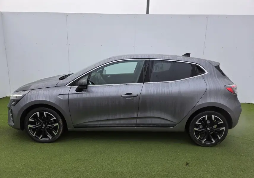 Profil droit d'une Renault Clio 2025 gris schiste métal avec jantes alliage noires et contour de vitres chromé.