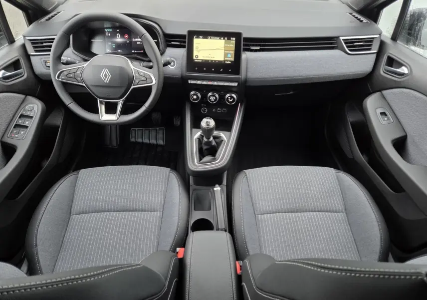 Vue intérieure avant de la Renault Clio 2025, tableau de bord gris mélangé avec volant multifonction et boîte manuelle.