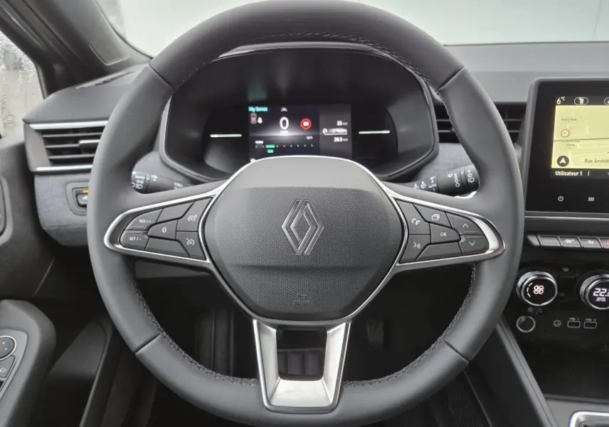 Vue intérieure centrée sur le volant multifonction noir de la Renault Clio 2025 avec tableau de bord numérique et écran tactile.