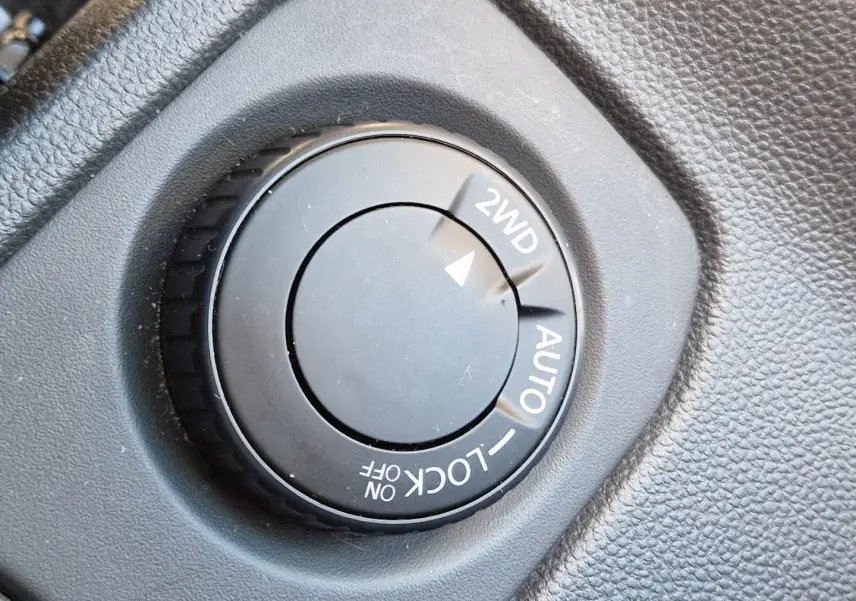 Gros plan sur le sélecteur de mode 4x4 dans l'habitacle du Dacia Duster blanc 2024, version Expression+ avec jantes alu 17 pouces.