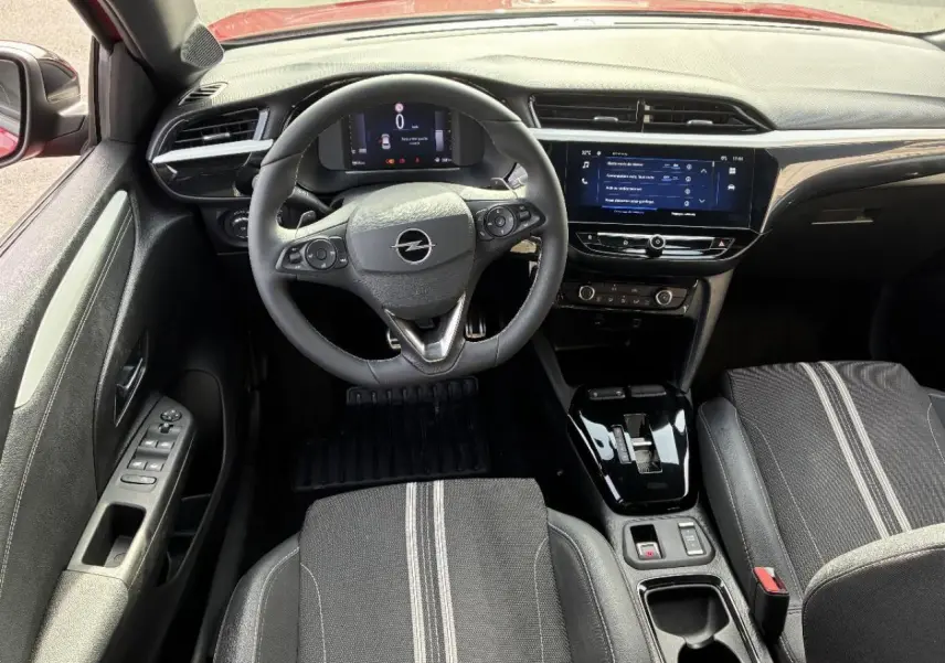 Vue intérieure de face de l’Opel Corsa 2025 hybride, montrant le volant, tableau de bord digital et console centrale noire brillante.