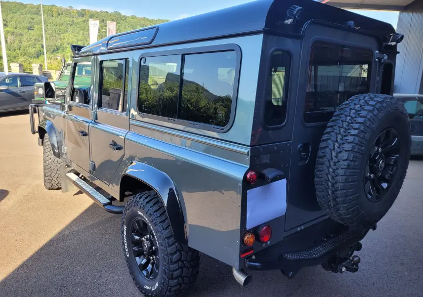 Vue 3/4 arrière droite d'un Land Rover Defender 110 Edition Limiter gris avec roue de secours et pneus tout-terrain.