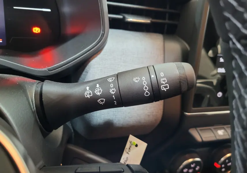 Gros plan sur la manette d'essuie-glace à gauche du volant dans l'habitacle gris clair de la Renault Clio 2025.