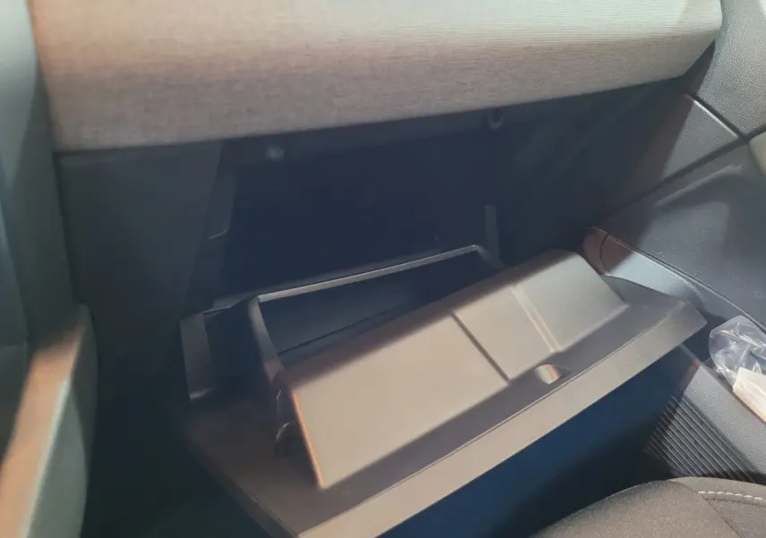 Gros plan sur la boîte à gants ouverte côté passager de la Renault Clio gris foncé Evolution Blue dCi 100 2025.