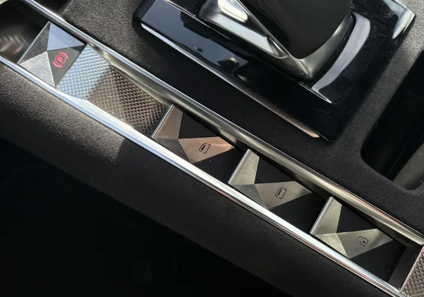 Gros plan sur les commandes de lève-vitres et frein de stationnement du DS7 1.6 E-Tense Cristal Pearl, intérieur noir Alcantara.