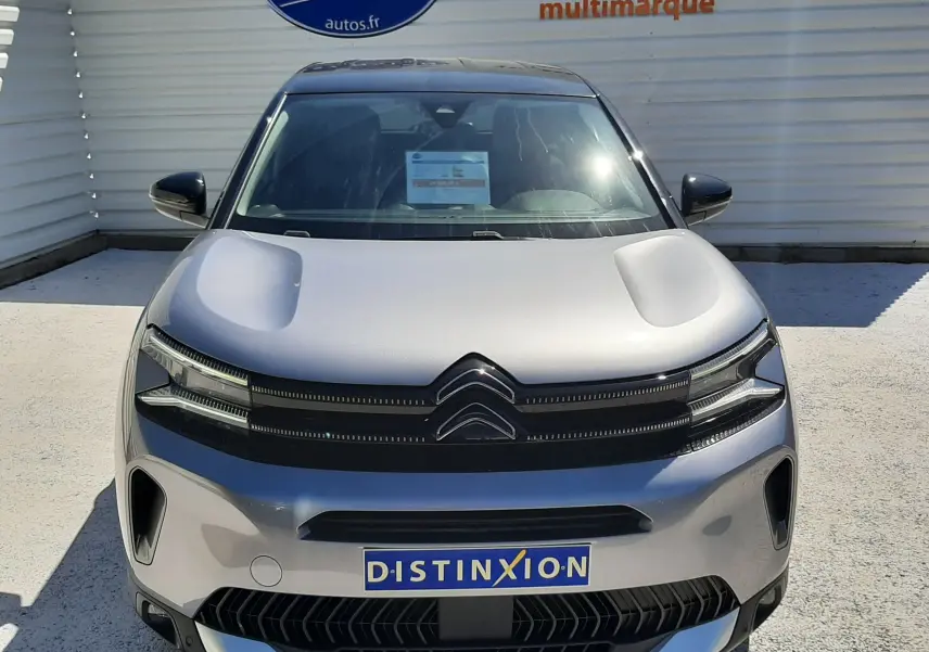 Vue avant d'un Citroën C5 Aircross Hybrid gris acier avec toit noir, calandre distinctive et logo Citroën visible.
