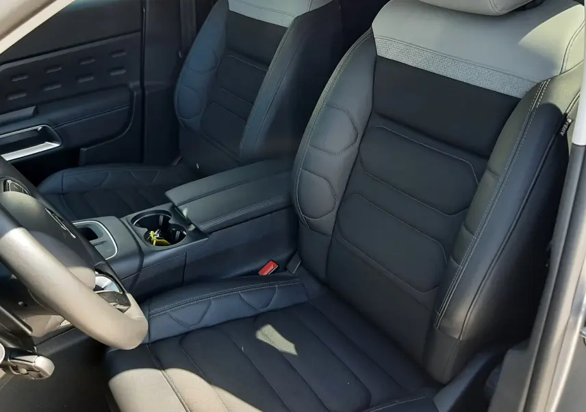 Vue intérieure côté conducteur du Citroën C5 Aircross Hybrid 2024, sièges bicolores gris clair et noir avec coutures apparentes.
