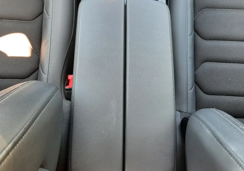 Vue plongeante sur l'accoudoir central gris noir et les sièges tissu cuir du Citroën C5 Aircross Hybrid 2024.