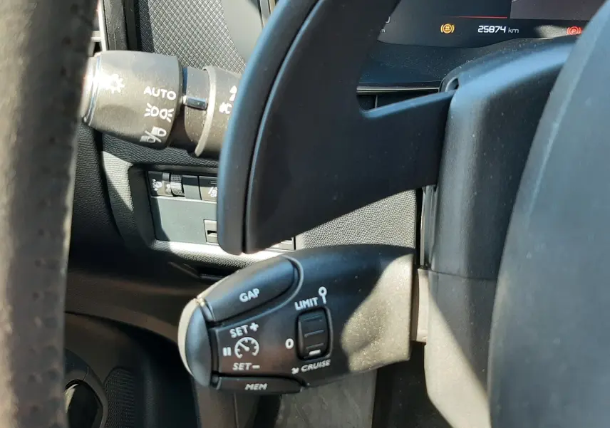 Gros plan sur la commande de régulateur de vitesse au volant d’un Citroën C5 Aircross Hybrid 2024, intérieur gris noir.