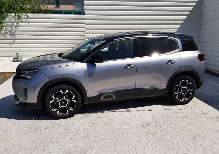 Vue de profil côté gauche du Citroën C5 Aircross Hybrid gris acier avec toit noir, roues à jantes noires et détails noirs.