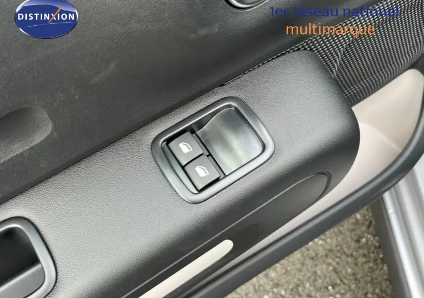 Détail des commandes des vitres électriques sur la porte avant gauche d'une Citroën C3 gris Artense 2024.
