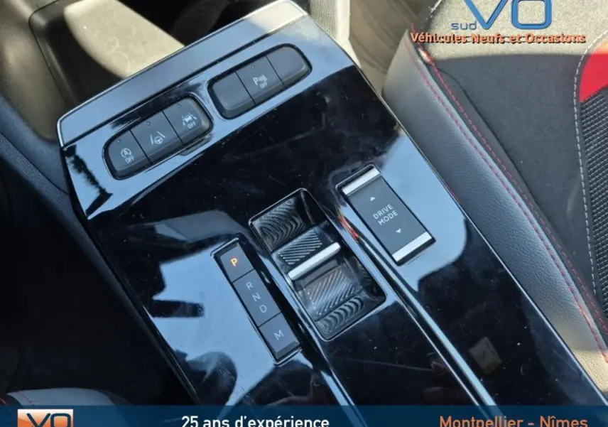 Gros plan sur la console centrale noire brillante de l'Opel Mokka gris clair, avec commandes de boîte auto et mode de conduite.