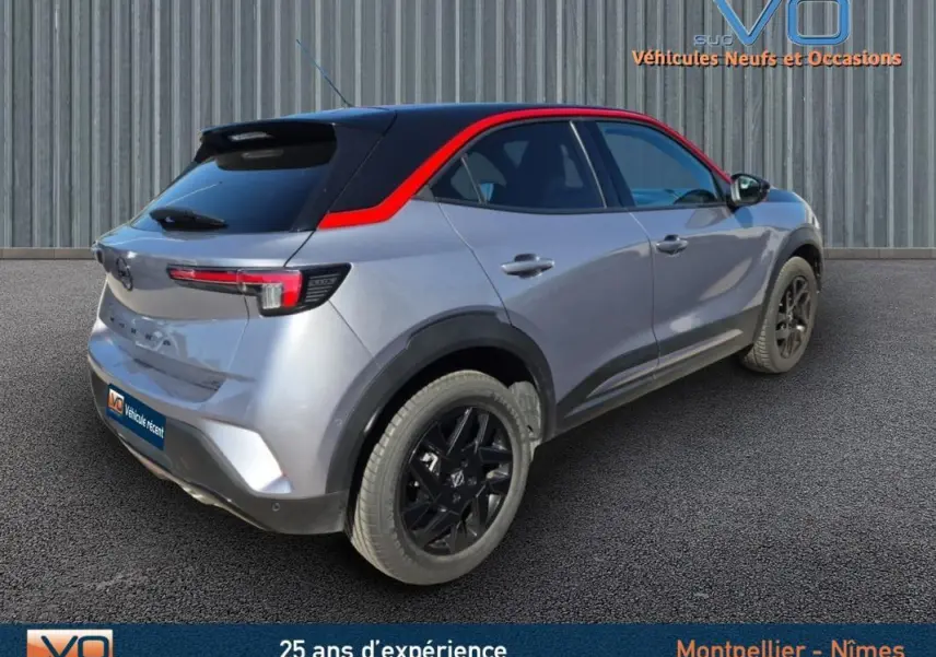 Opel Mokka gris clair vue 3/4 arrière droit avec toit noir et liseré rouge, jantes alliage noires 18 pouces.