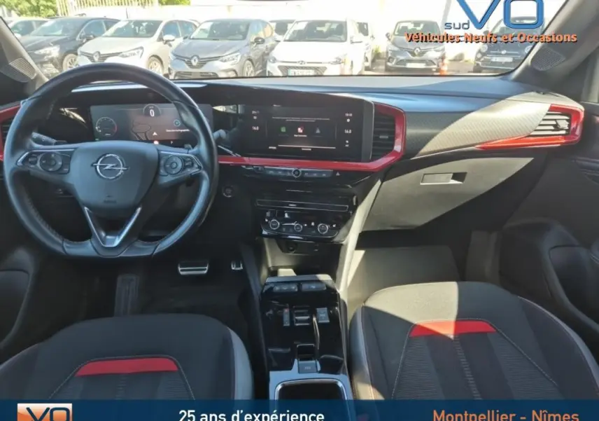 Intérieur avant de l'Opel Mokka 2022, tableau de bord noir avec inserts rouges et volant cuir multifonction.