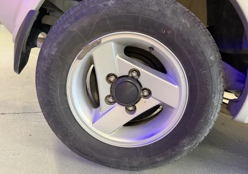 Gros plan sur la jante alu grise du côté gauche d'un Suzuki Jimny Cabriolet 2005 avec pneu tout-terrain.