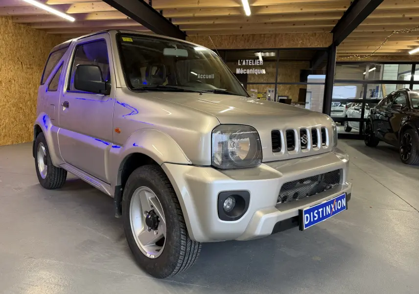 Suzuki Jimny Cabriolet gris vue 3/4 avant droit en intérieur, avec jantes alu et hard-top fermé.