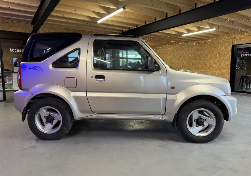 Vue de profil côté gauche d'un Suzuki Jimny Cabriolet gris 2005 avec hard-top et jantes alu en intérieur.