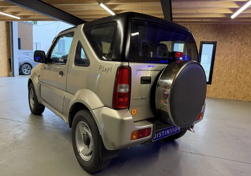 Vue 3/4 arrière droite d'un Suzuki Jimny Cabriolet gris 2005 avec hard-top, roue de secours et jantes alu.