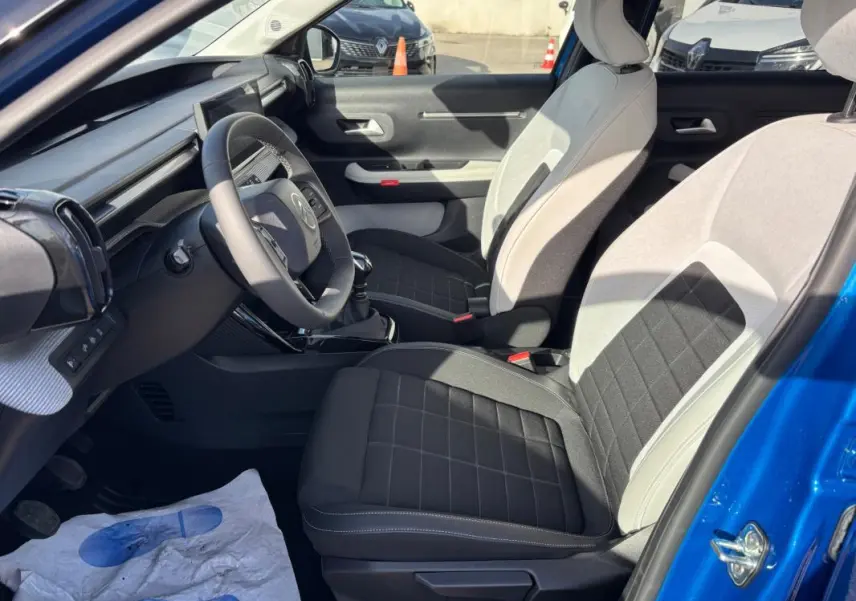 Vue intérieure côté conducteur de la Citroën C3 bleu 2025, sièges bi-ton noir et gris, volant et tableau de bord visibles.