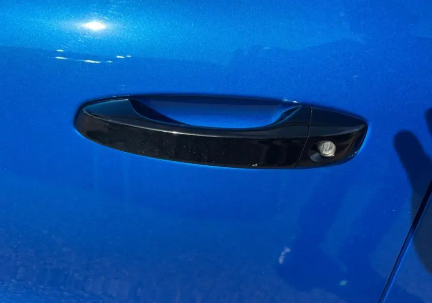 Poignée de porte noire sur la porte avant gauche d'une Citroën C3 bleu vif 2025, détail extérieur.