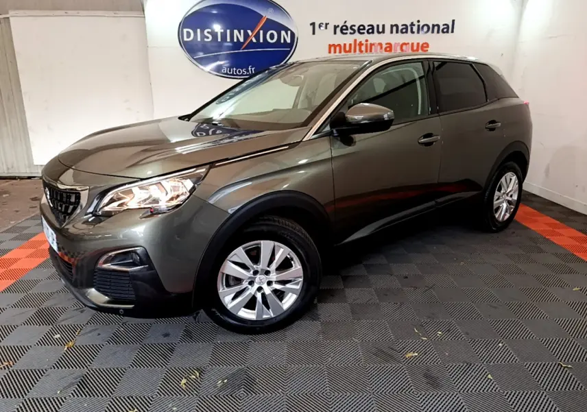 Peugeot 3008 gris foncé vue 3/4 avant droit, avec phares allumés et jantes alliage en showroom.