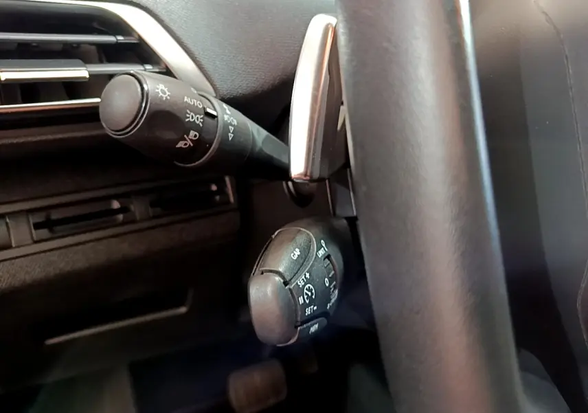 Gros plan sur commandes au volant cuir du Peugeot 3008 2020, montrant régulateur et commodo éclairage côté gauche.