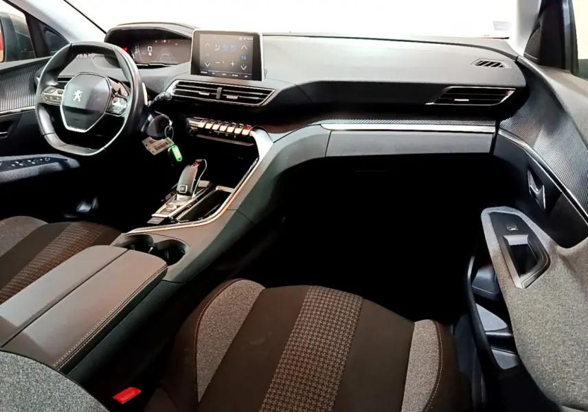 Intérieur du Peugeot 3008 2020 vu côté passager, tableau de bord noir avec écran tactile et volant cuir.