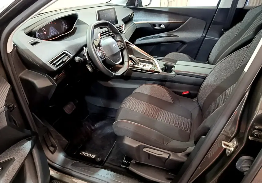 Intérieur avant droit du Peugeot 3008 gris foncé 2020, volant cuir, tableau de bord digital et sièges tissu gris.