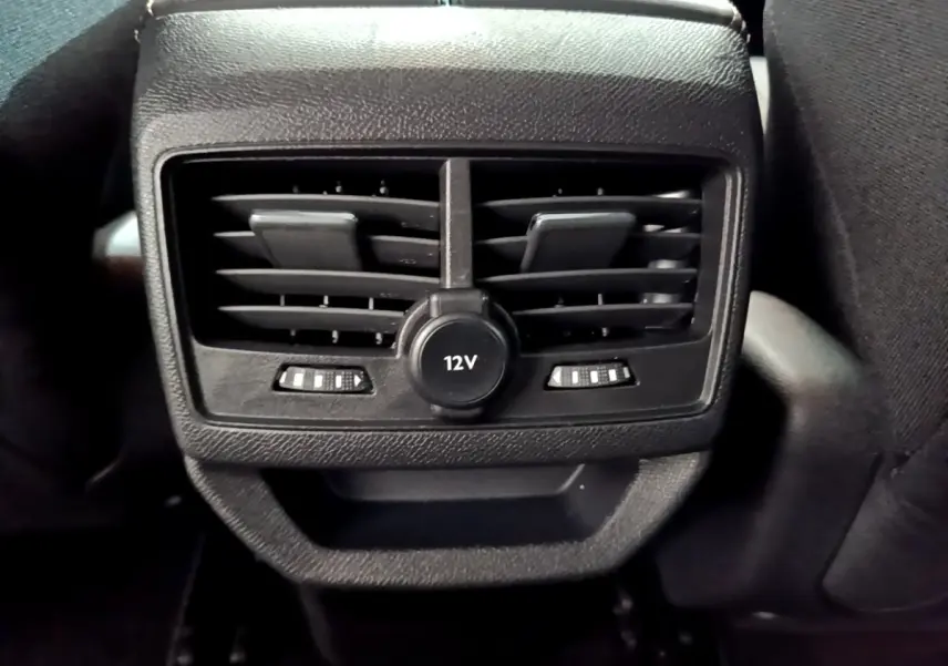 Prise 12V et aérateurs arrière noirs du Peugeot 3008 gris foncé, vue rapprochée de la console centrale arrière.